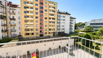 Blick vom Balkon auf die umliegenden Wohngebäude und den Parkplatz bei sonnigem Wetter.