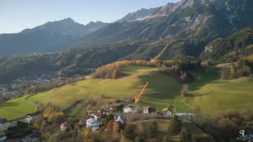 Luftaufnahme des Anwesens in einer malerischen Berglandschaft mit umliegenden Häusern und grünen Wiesen.