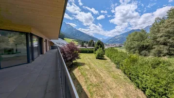 Langer Balkon mit Glasgeländer und weitem Blick über das Tal und die Berge.