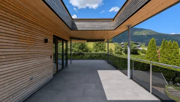 Große, moderne Terrasse mit Holzelementen und weitem Blick auf die umliegende Berglandschaft.