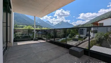 Geräumiger Balkon mit Glasbrüstung und atemberaubendem Blick auf die umliegende Berglandschaft.