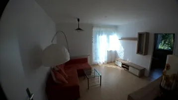 Helles Wohnzimmer mit rotem Sofa, Holzboden und Zugang zu einem Balkon.