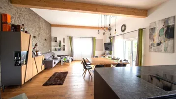 Geräumiger offener Wohn- und Essbereich mit Holzbalken, Parkettboden und moderner Einrichtung.