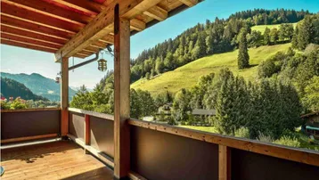 Großer Holzbalkon mit Bergblick und grüner Landschaft.