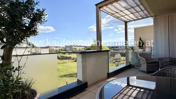 Geräumige Terrasse mit Pergola, modernen Glasgeländern und weitem Blick ins Grüne.