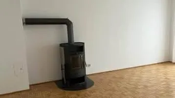 Wohnzimmer mit Holzparkettboden und einem modernen Holzofen, der für gemütliche Wärme sorgt.