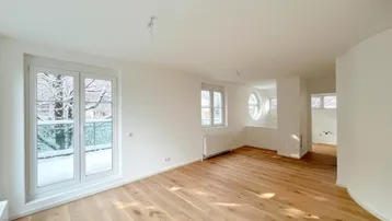 Geräumiges, helles Wohnzimmer mit Eichenparkett, großen Fenstern und Blick auf die verschneite Natur.