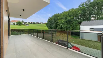 Großer Balkon mit Glasgeländer und weitem Blick über die Landschaft.