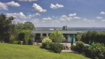 Modernes Haus mit weitläufigem Garten, Poolbereich und Panoramablick über die Stadt.