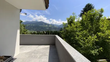 Geräumiger Balkon mit Fliesenboden und weitem Blick auf die umliegende Berglandschaft.