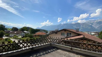 Geräumige Terrasse mit Holzzaun und weitem Blick auf die umliegende Berglandschaft und das Tal.