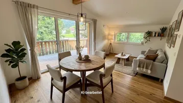 Heller Wohn- und Essbereich mit Holzboden, sichtbaren Holzbalken und Zugang zum Balkon.