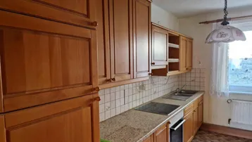Traditionelle Einbauküche mit Holzfronten, Granitarbeitsplatte und integriertem Kochfeld sowie Backofen.