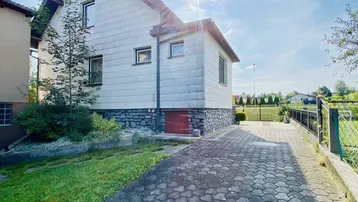 Seitenansicht des Hauses mit gepflasterter Auffahrt und sonnigem Wetter.
