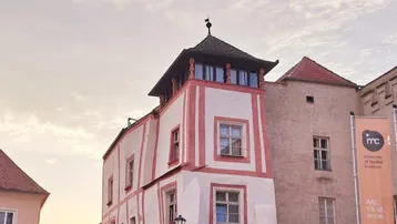 Altes, charmantes Gebäude mit markanter Fassade und Turm in einer historischen Gasse bei Sonnenuntergang.