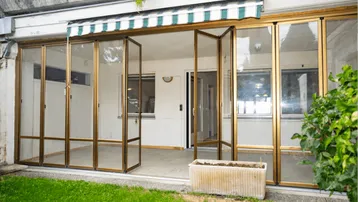 Verglaste Terrasse mit Markise und Zugang zum kleinen Gartenbereich, ideal für entspannte Stunden im Freien.