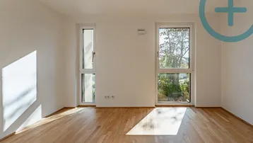 Lichtdurchflutetes Zimmer mit Parkettboden und Blick ins Grüne durch die großen Fenster.