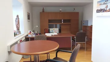 Geräumiges Büro mit Holzboden, großem Schreibtisch und Besprechungstisch, ausgestattet mit Holzschränken.