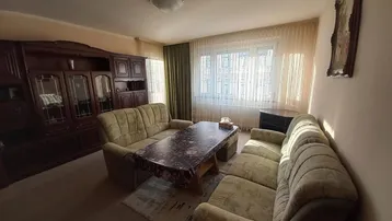 Gemütliches Wohnzimmer mit traditionellen Möbeln, zwei Sofas und einem großen Fenster, das viel Licht hereinlässt.
