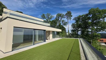 Moderne Architektur mit großer Dachterrasse, Kunstrasen und weitem Blick in die Landschaft.