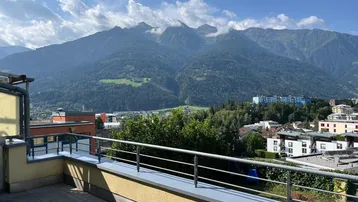 Geräumige Terrasse mit Fliesenboden und beeindruckendem Bergblick unter blauem Himmel.