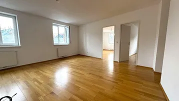 Helles, leeres Zimmer mit Parkettboden und zwei Fenstern, bereit zur individuellen Gestaltung.