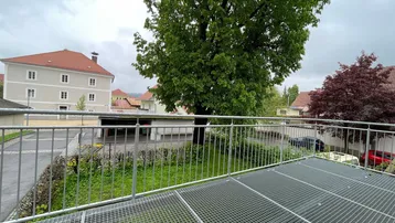 Blick von einem Balkon mit Metallgitterboden auf die Umgebung und umliegende Gebäude.