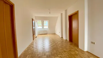 Geräumiger Wohnbereich im Dachgeschoss mit Parkettboden, Dachfenstern und viel natürlichem Licht.