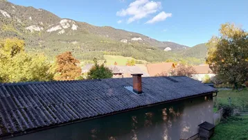 Weitläufiger Blick auf bewaldete Berge und die Dächer der umliegenden Häuser.