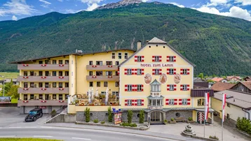 Luftaufnahme eines Hotels mit traditioneller Architektur, umgeben von grünen Bergen und einem blauen Himmel.