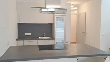 Moderne Küche mit Kochinsel, weißen Schränken und Dunstabzugshaube, ideal für offenes Wohnen.