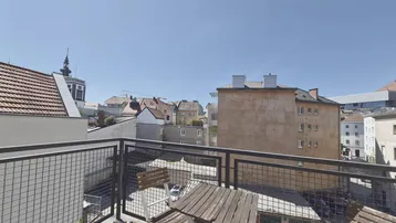 Sonniger Balkon mit Stadtblick und Sitzgelegenheiten, ideal für entspannte Stunden im Freien.