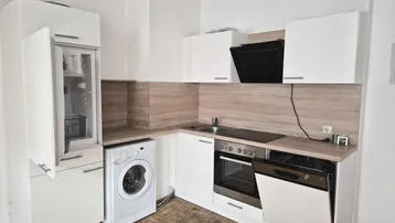 Funktionale Einbauküche in Weiß mit integrierten Geräten und Waschmaschine.