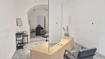 Heller, moderner Friseursalon mit weiß gestrichenen Wänden, gewölbter Decke und großen Spiegeln.
