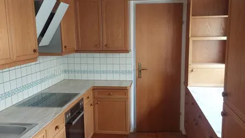 Funktionale Küche mit hellen Holzschränken, Fliesenrückwand und integrierten Geräten.
