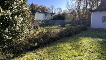 Weitläufiger Gartenbereich mit Rasenfläche und Blick auf ein weiteres Gebäude in der Ferne.