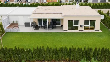 Modernes Einfamilienhaus mit gepflegtem Garten, großer Terrasse und Hecke als Sichtschutz.