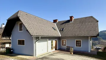 Traditionelles Einfamilienhaus mit Satteldach, Garage und gepflasterter Auffahrt in ländlicher Umgebung.