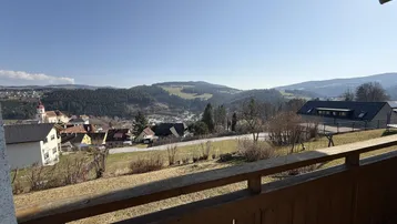 Balkon mit Holzboden und weitem Blick über die umliegende Landschaft und das malerische Dorf.