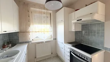 Funktionale Küche mit weißen Schränken, Fliesenrückwand und einem Fenster für Tageslicht.
