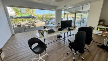 Geräumiges Büro mit großen Glasfronten, die viel Tageslicht hereinlassen und einen Blick nach draußen bieten.