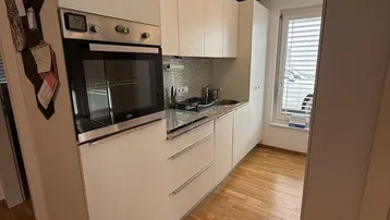 Moderne Einbauküche mit hellen Fronten, Granitarbeitsplatte und integriertem Backofen.