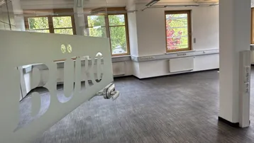 Geräumiges Büro mit großen Fenstern, die viel Tageslicht hereinlassen und einen Blick ins Grüne bieten.