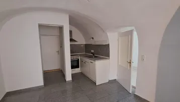 Kleine Küche mit Gewölbedecke und Fliesenboden, ausgestattet mit Herd und Spüle.