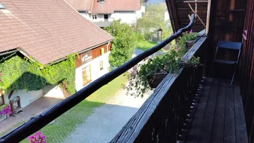 Traditioneller Holzbalkon mit Blumenkästen bietet einen Blick auf den Innenhof und die umliegenden Häuser.
