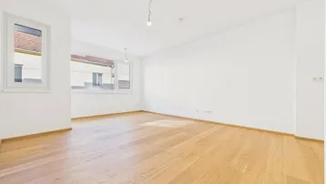 Helles, leeres Zimmer mit modernem Holzparkett und großen Fenstern, bereit zur individuellen Gestaltung.