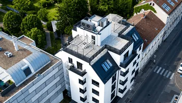Moderne Wohnanlage mit Flachdach und Dachterrassen in städtischer Umgebung.