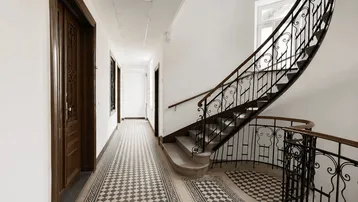 Heller Flur mit kunstvollem Fliesenboden und einer eleganten geschwungenen Treppe mit schmiedeeisernem Geländer.