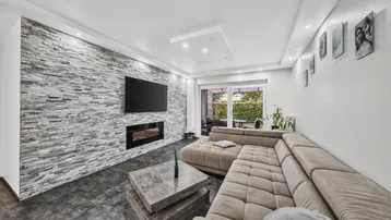 Modernes Wohnzimmer mit Steinwand, Kamin und Zugang zur Terrasse.