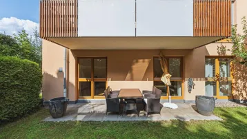 Große Terrasse mit Gartenmöbeln und direktem Zugang zum gepflegten Rasenbereich.